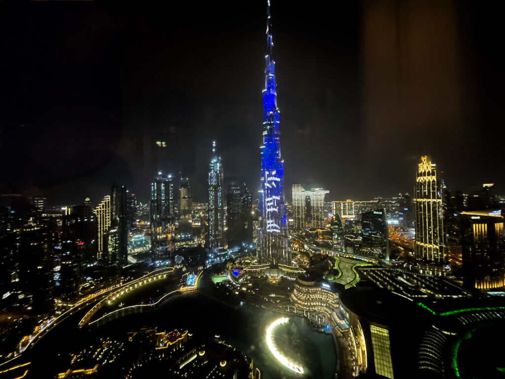 A cityscape of Dubai lit up at night, with Burj Khalifa at the center