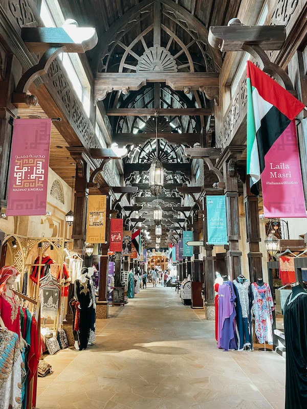 the corridor of an indoor bazaar with clothing stalls on both sides