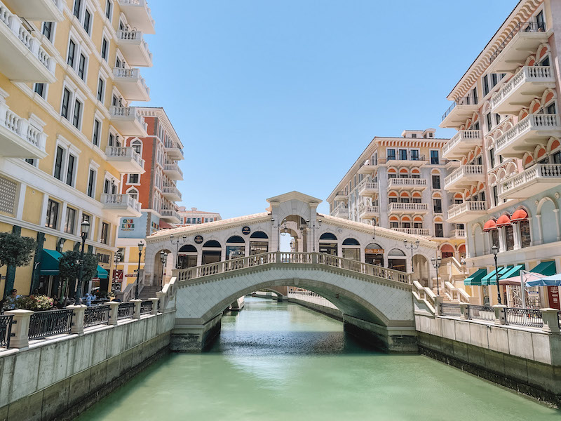 A canal in The Pearl Qatar with a bridge crossing it, and beautiful buildings on both sides