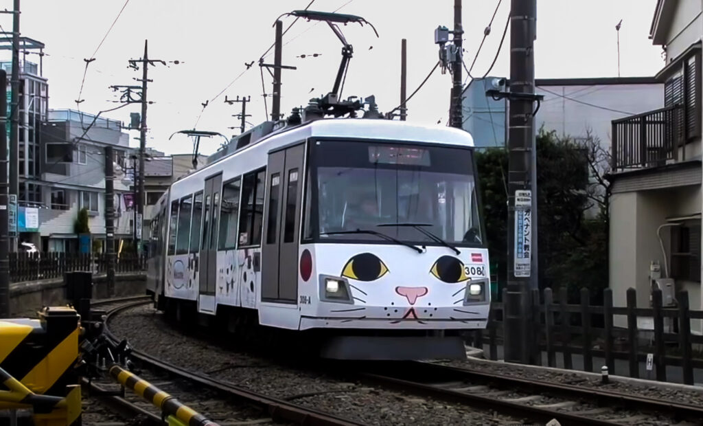 A tram with Maneki Neko drawings on a railway