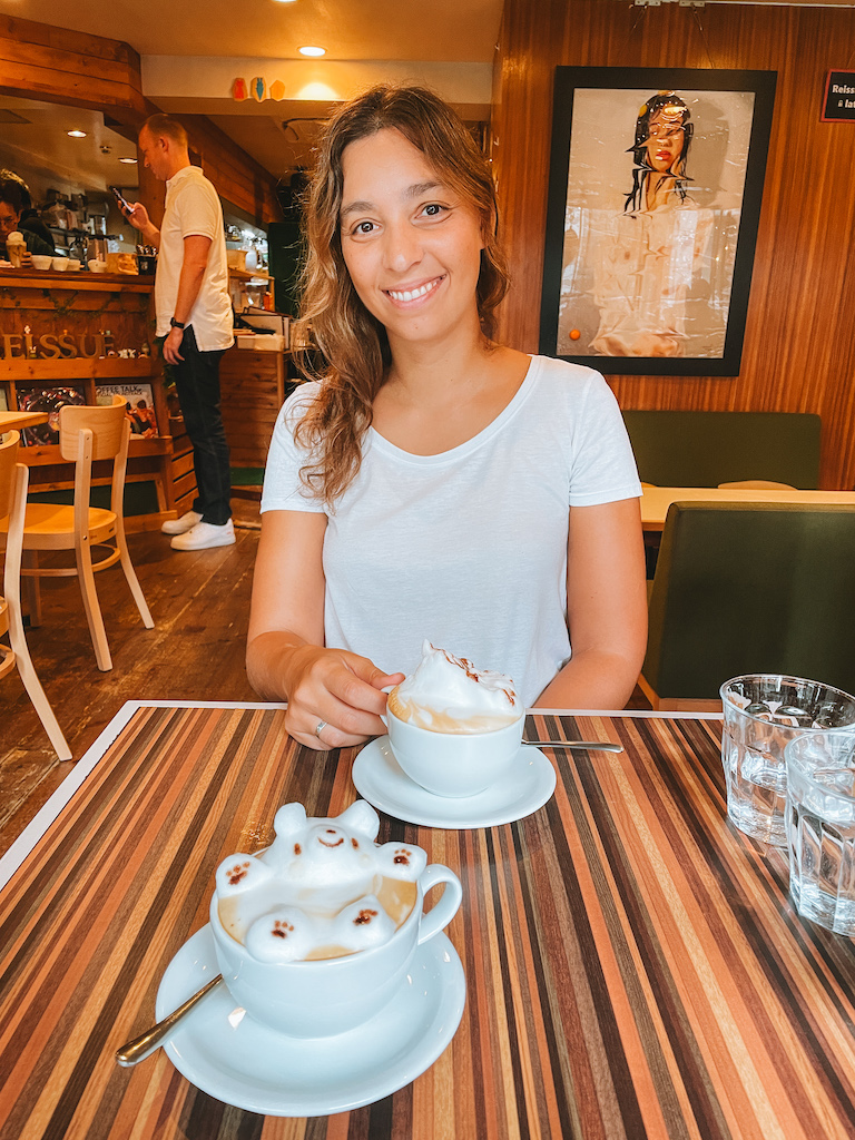 A woman smiling and two coffee mugs with 3D latte art on a table