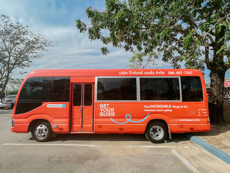 Orange GetYourGuide tour bus used for day trips from Bangkok to Ayutthaya's ruins.