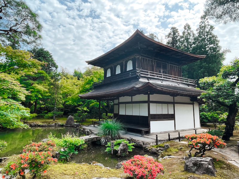 A Japanese temple surrounded by ponds, flowers, and trees