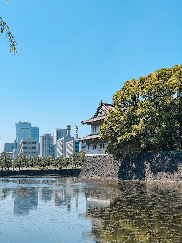 Tokyo's Imperial Palace with a body of water in front and skyscrapers in the background.