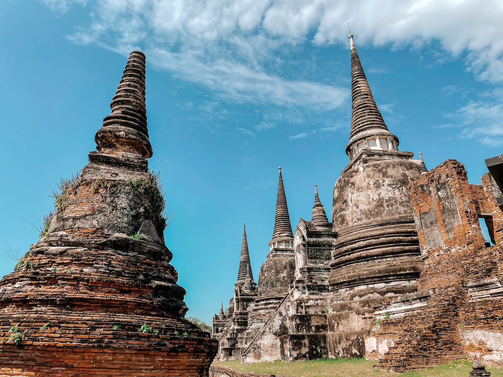 Ancient white and brick stupas reaching into blue sky at Wat Phra Si Sanphet temple in Ayutthaya.