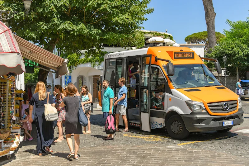 A small white and orange van and people descending 