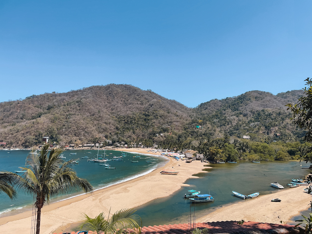 A long stretch of sand with bodies of water on both sides, and mountains in the background