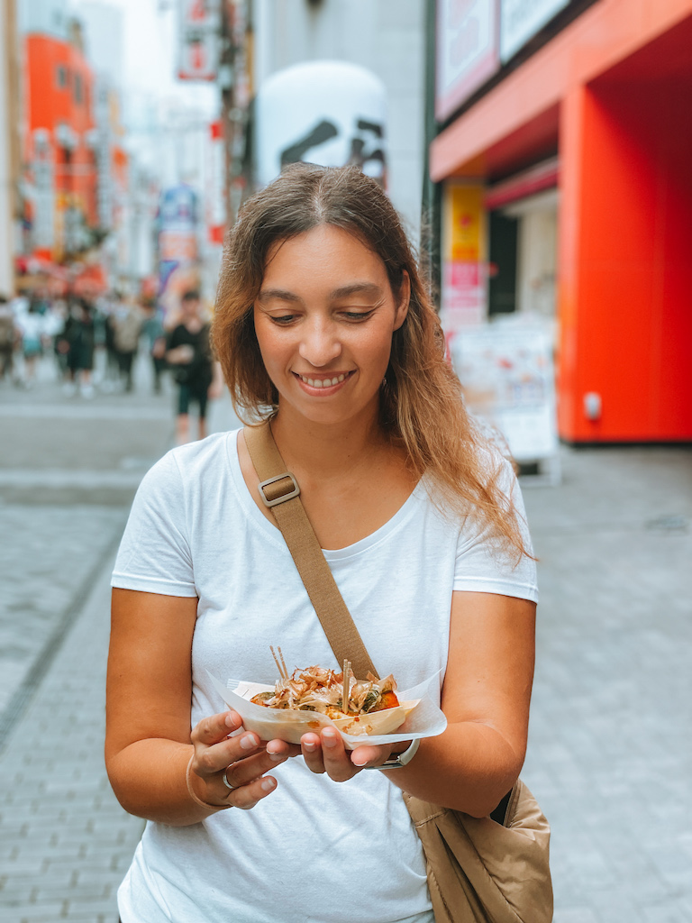 A woman holding a plastic tray with street food 