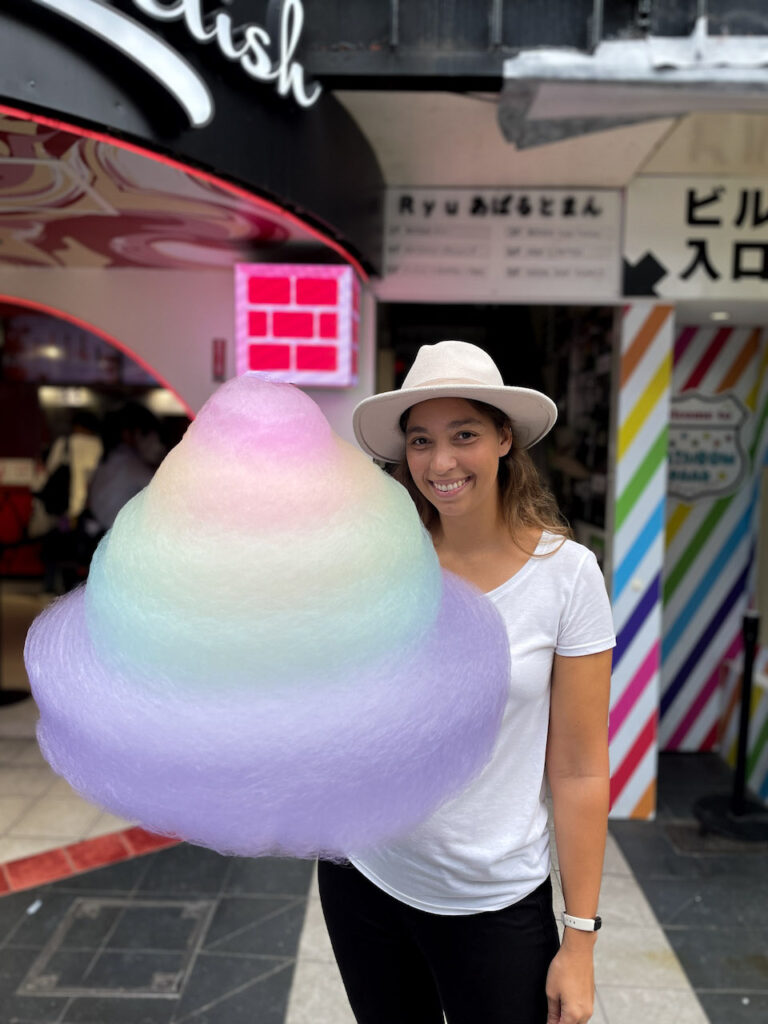 A woman holding a massive rainbow cotton candy