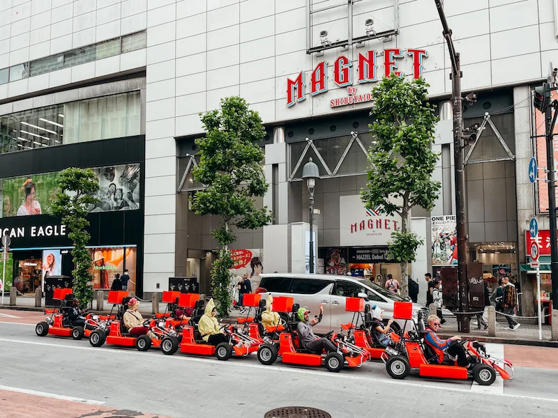 people in red karts in front of a large building 