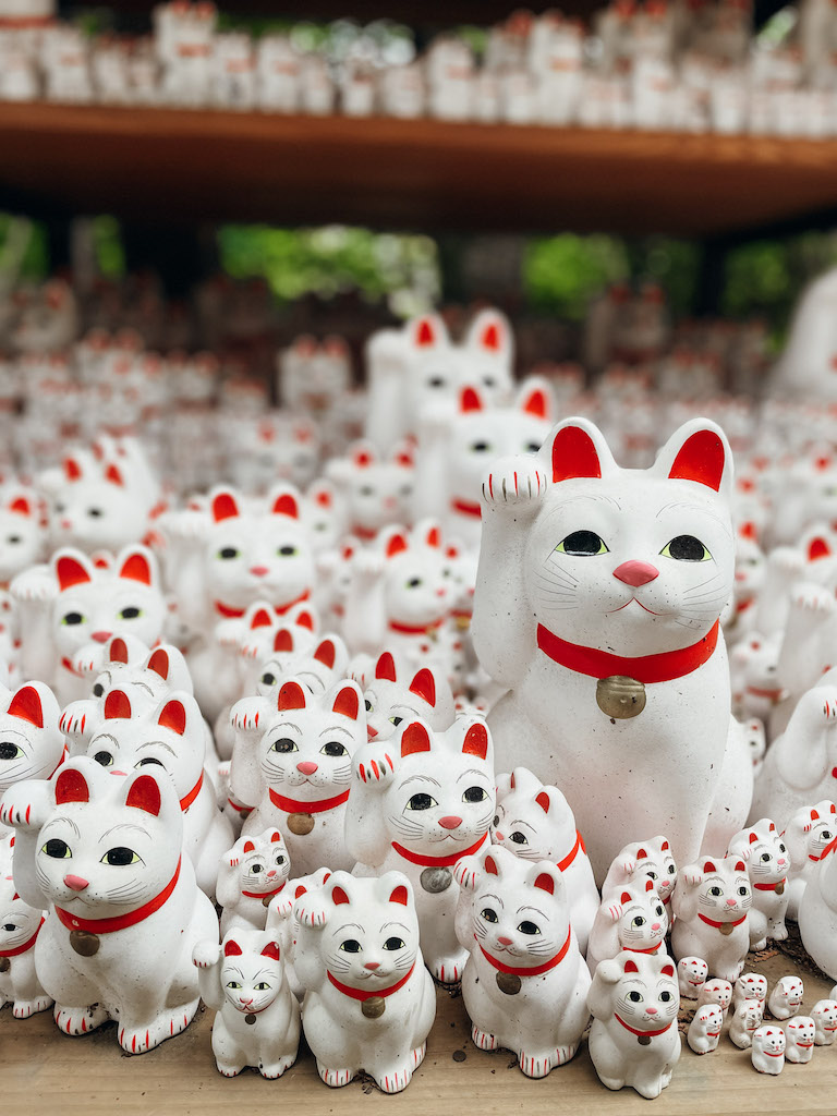 red and white Maneki Neko figurines of various sizes