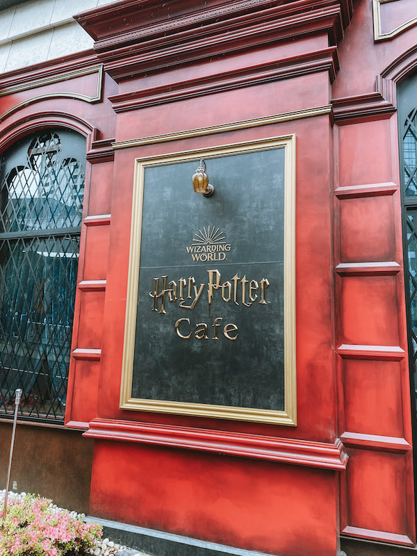 A sign that reads Harry Potter Cafe outside a red building