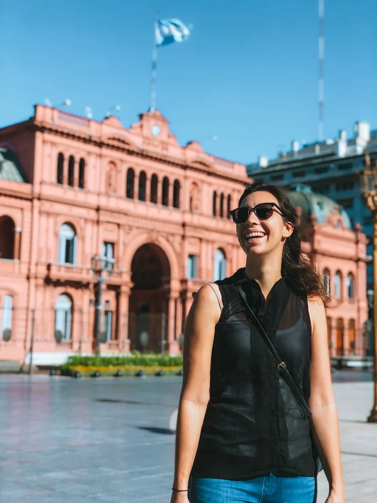 A woman smiling in front of the Presidential Pink House in Buenos Aires