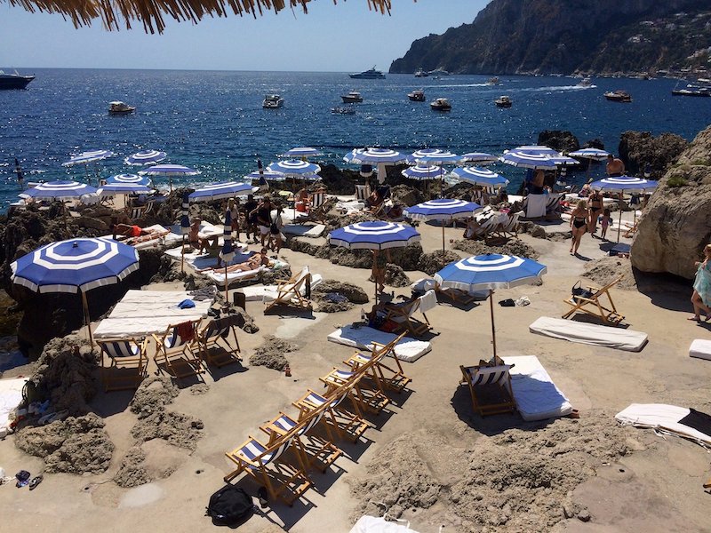 Blue and white sun umbrellas on the beach, and the sea in the background