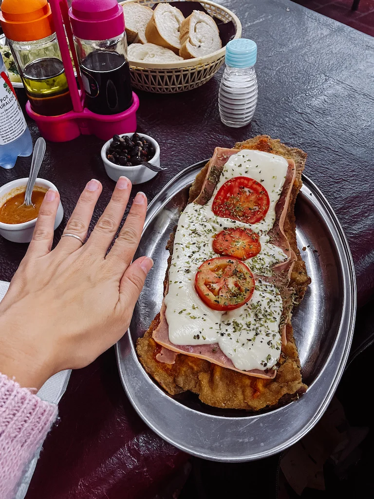 A milanesa dish with cheese and tomato slices on top