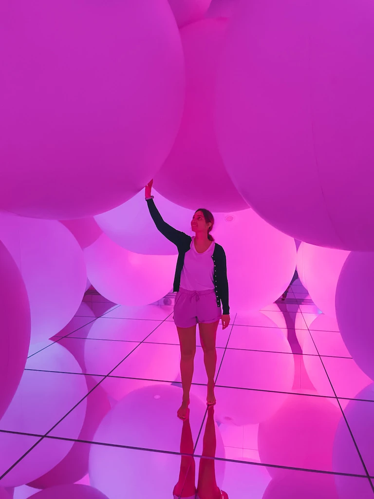 A woman inside a pink room with giant balloons