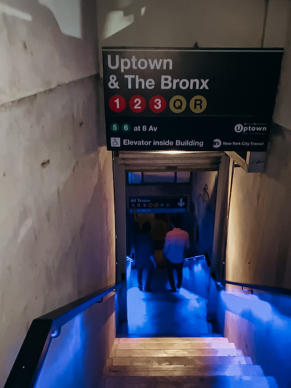 A staircase leading down to an underground bar and a sign that reads Uptown & the Bronx