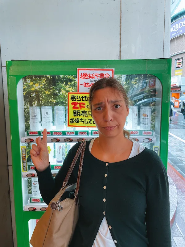 A woman standing in front of a green vending machine 