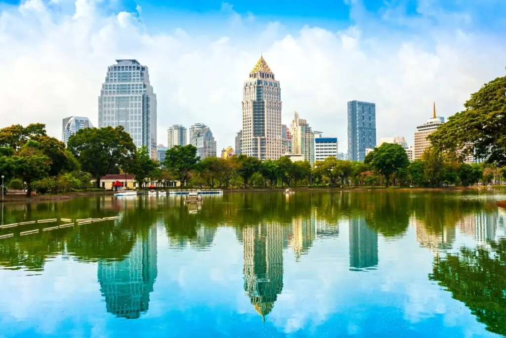 A peaceful lake reflecting the trees and skyscrapers in front of it 