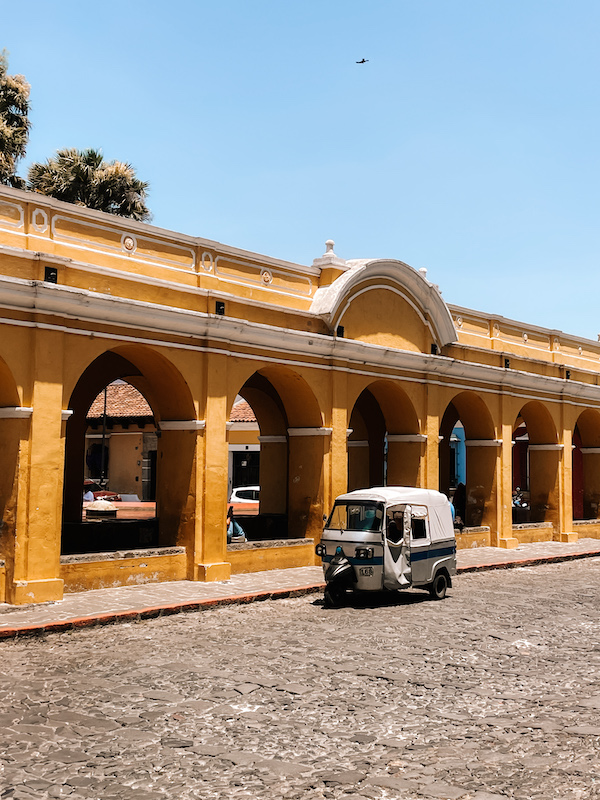 A yellow building, and a grey rickshaw vehicle parked outside