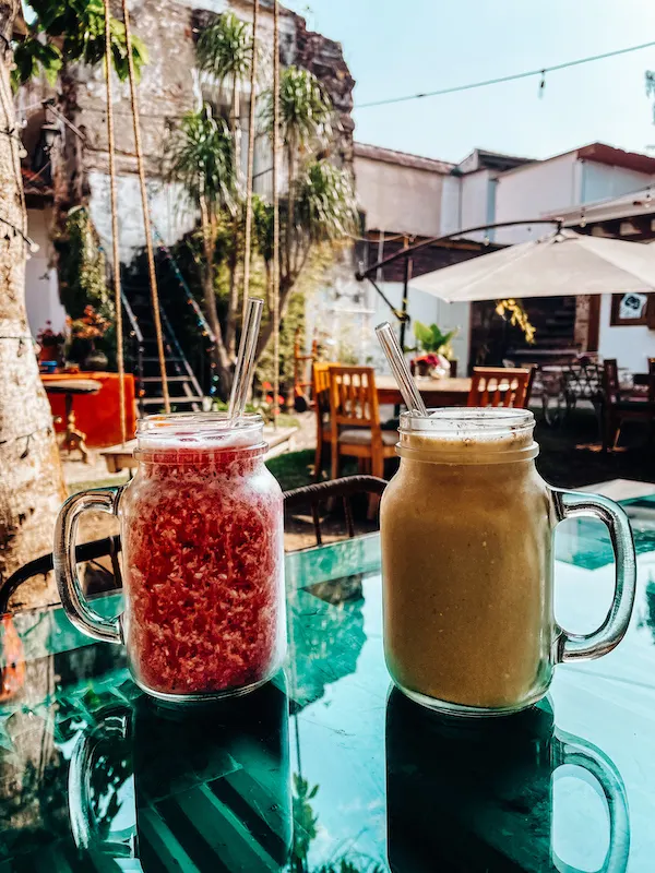 Two jar glasses with drinks on a glass table 