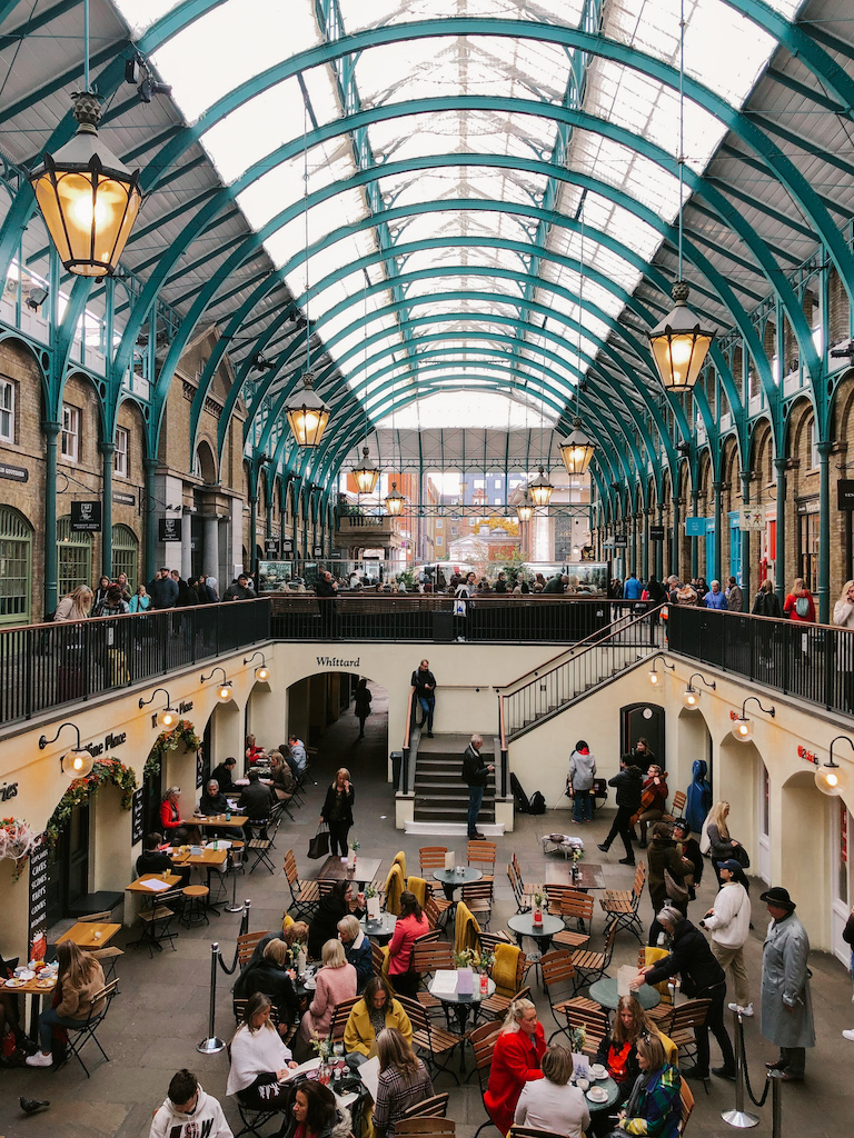 The interior of Covent Garden, with a courtyard full of tables and chairs, lined by restaurants