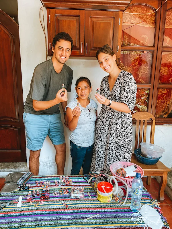 Two women and a man holding small handicrafts and smiling at the camera