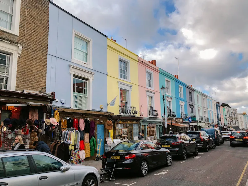 A road lined with markets showcasing their clothes and products, and pastel-colored houses