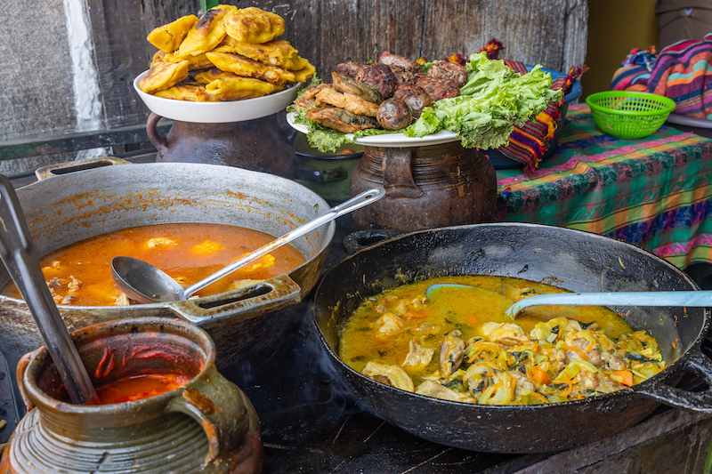 Two large pots with stews, and more food in the background