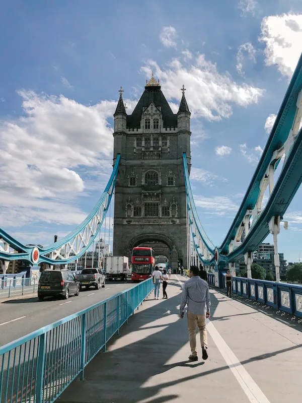 The Tower Bridge photographed from the middle of the bridge, with one of the towers in the center and people walking toward it 